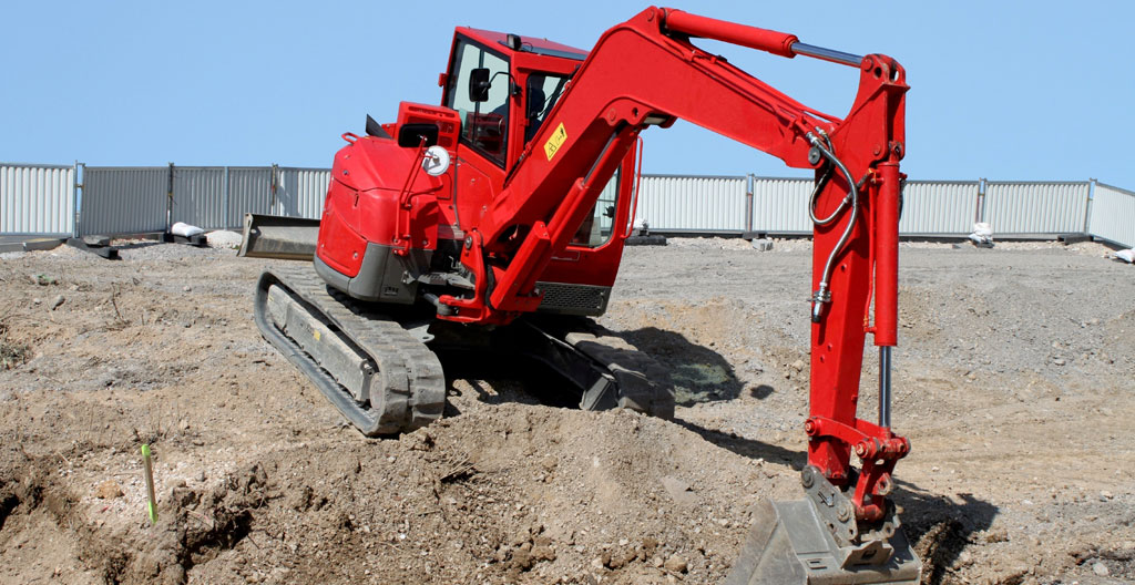 Minipelle de 3 tonnes en action sur un chantier urbain français avec opérateur qualifié, bâtiments anciens en arrière-plan
